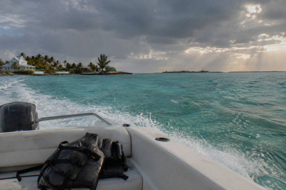 A speedboat cutting across shallow turquoise water toward distant small islands