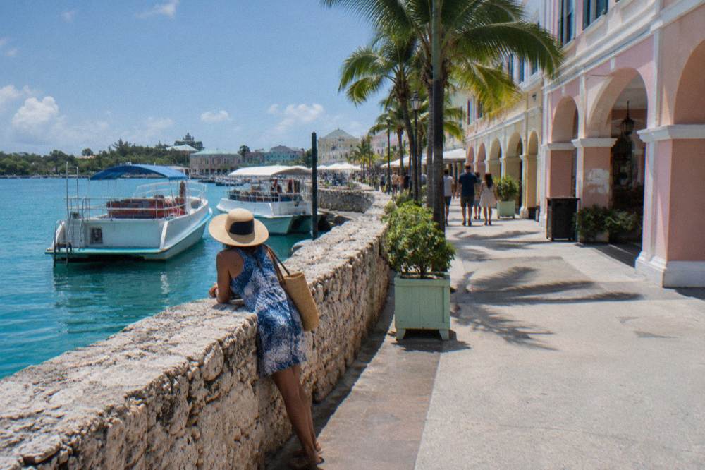 A busy waterfront promenade with tour boats moored along a stone quay