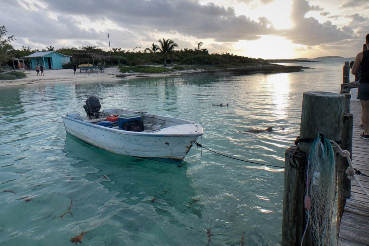 A calm turquoise bay with a small boat anchored off a white sand beach