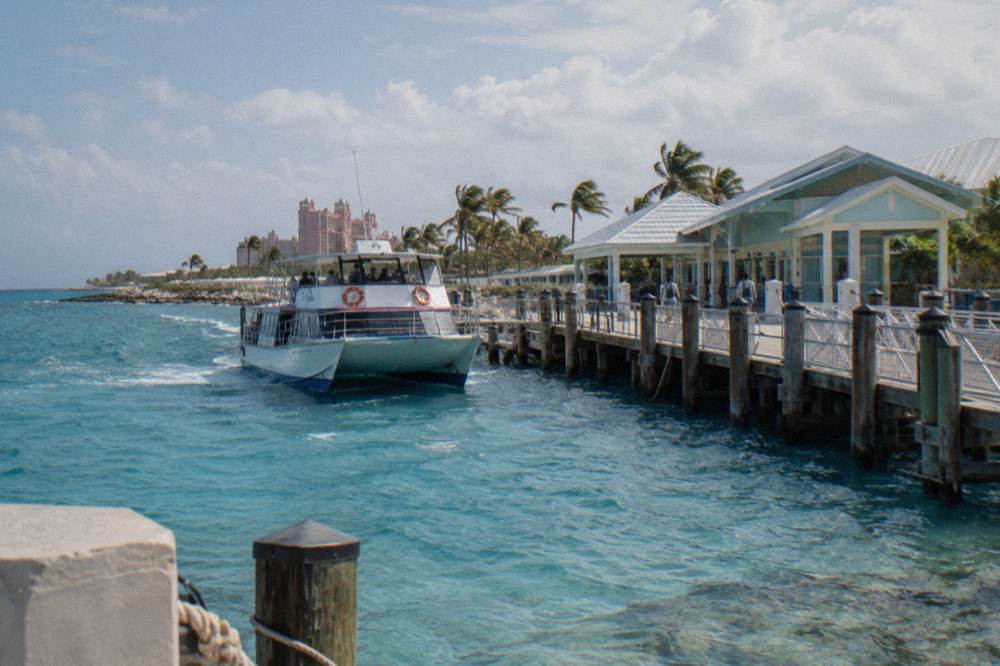 Tour boat approaching a wooden pier with clear shallow water below