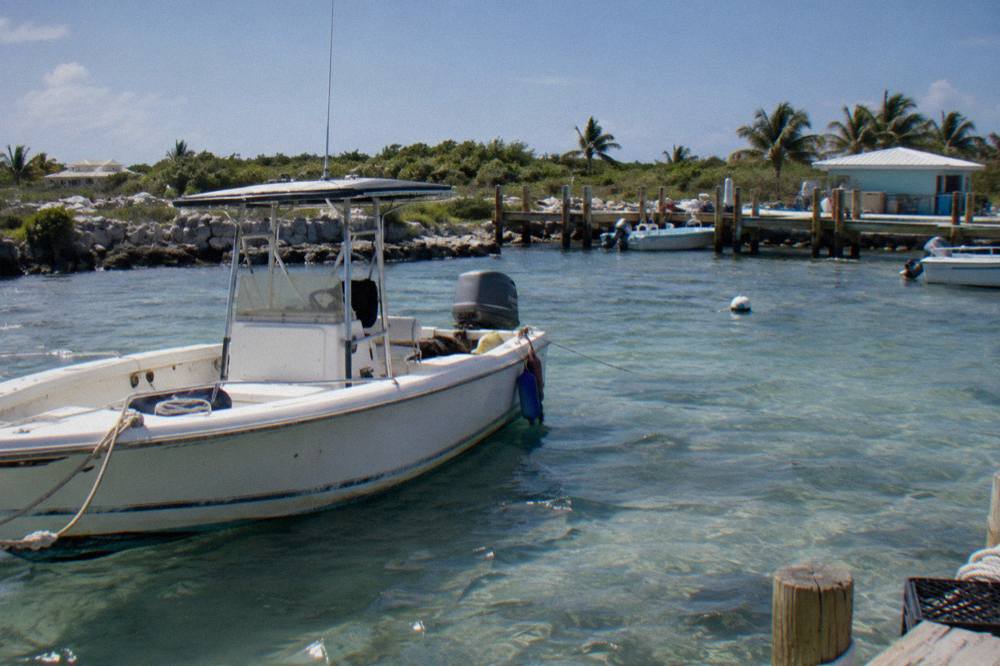 A speedboat anchored in clear shallow water beside a small Exuma cay