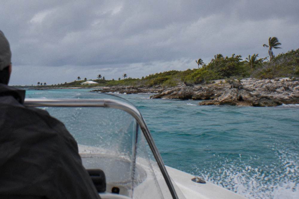 An open speedboat cutting across calm blue water between low islands