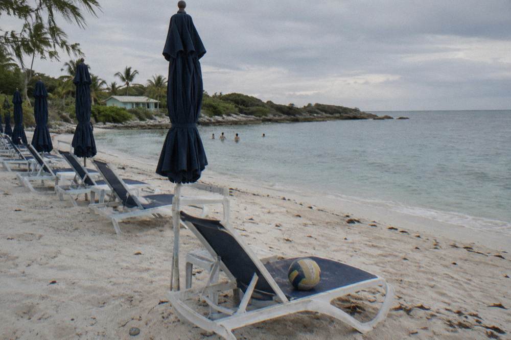 Shaded beach chairs and umbrellas on sand facing calm water