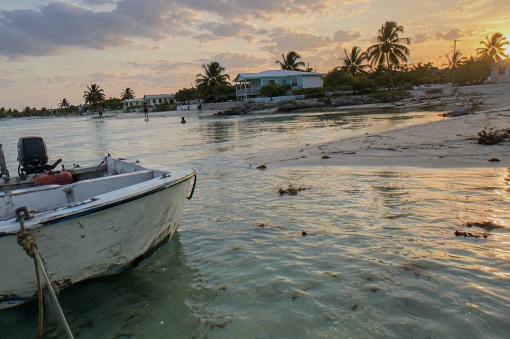 Small boat moored in clear shallow water beside a sandbar