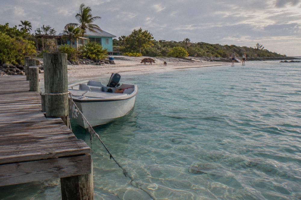 A small boat tied at a wooden dock over clear shallow water