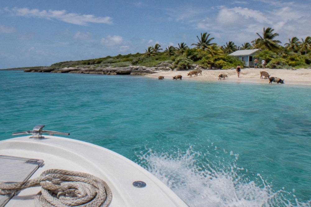 A powerboat crossing clear turquoise water toward a small Exuma island