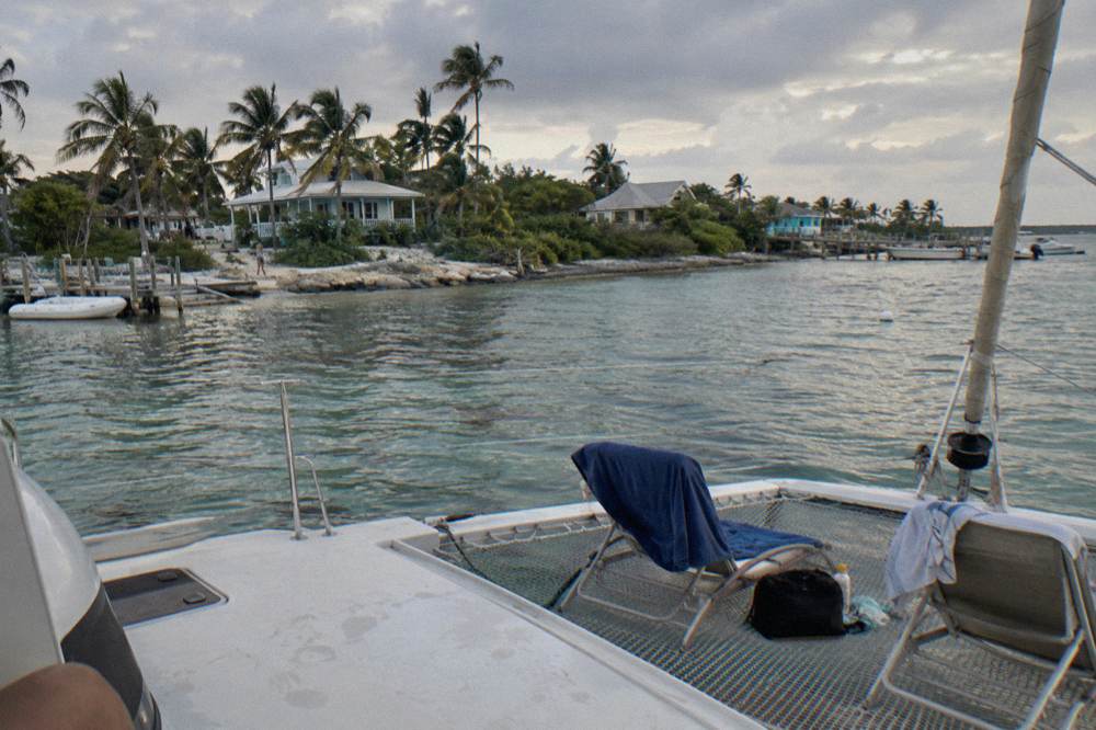 A catamaran anchored in a quiet Exuma bay with lounge chairs on deck