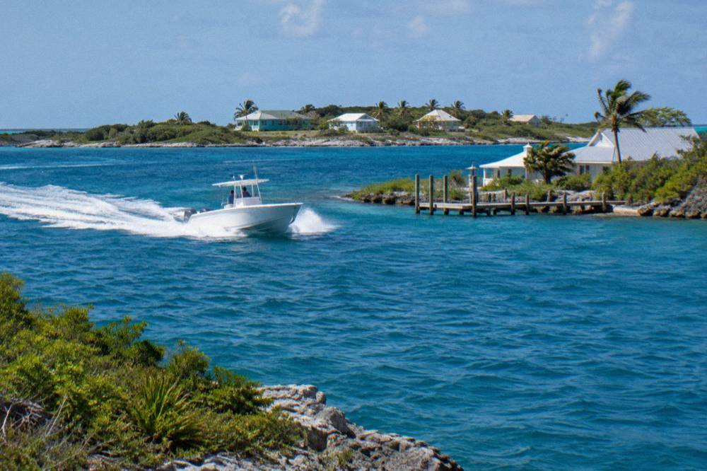 A powerboat cutting across open blue water between low Bahamian cays