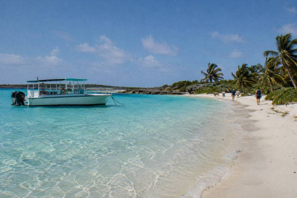 A tour boat anchored off a small beach with clear shallow water