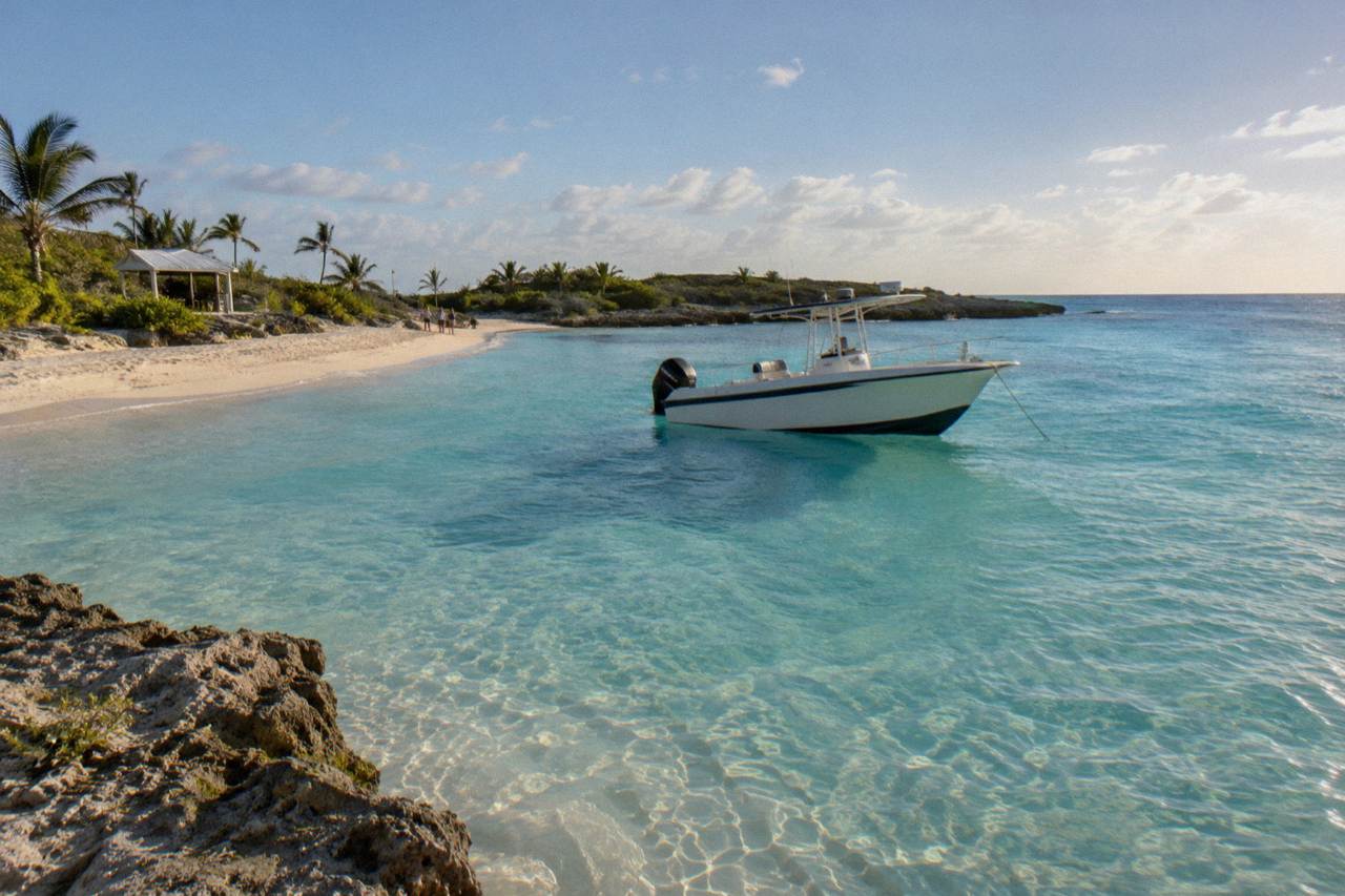 Turquoise shallows around a small Exuma cay with a speedboat anchored offshore