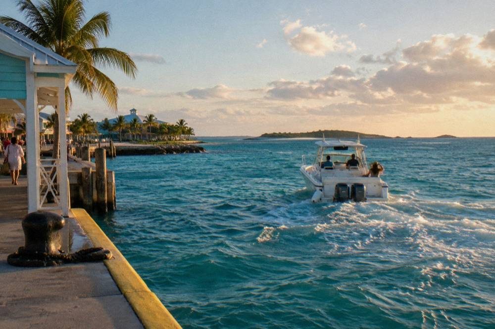 A powerboat cruising across open turquoise water toward low islands on the horizon