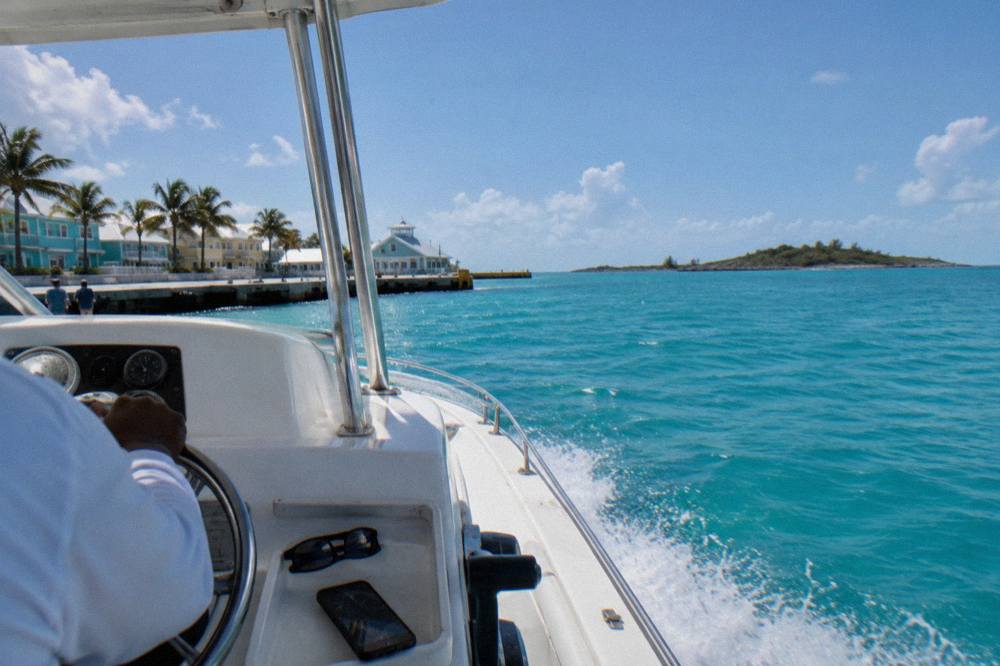 Open speedboat crossing calm turquoise water toward low green islands on the horizon