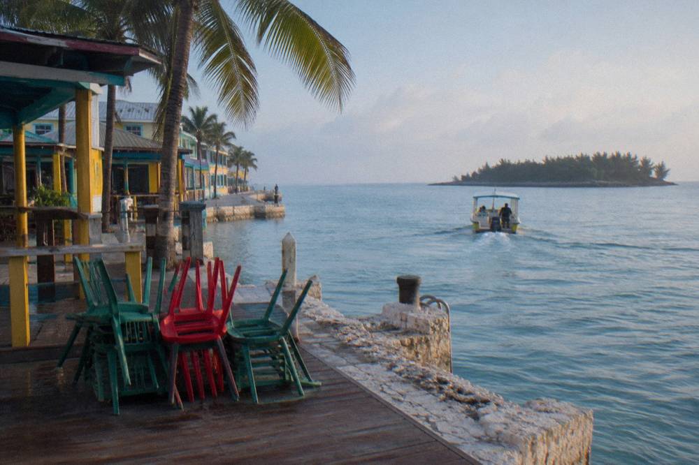 A small boat crosses clear turquoise water toward a green island