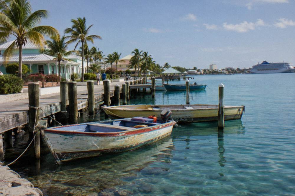 Wooden fishing skiffs moored in clear shallow water near a Nassau dock