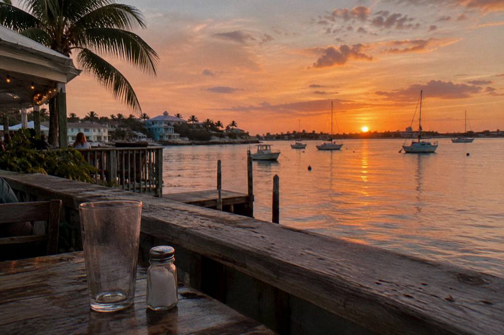 Sunset light over calm harbor water with boats at anchor