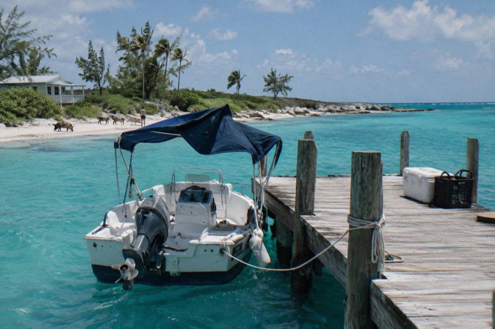 Small powerboat anchored in turquoise water beside a wooden dock