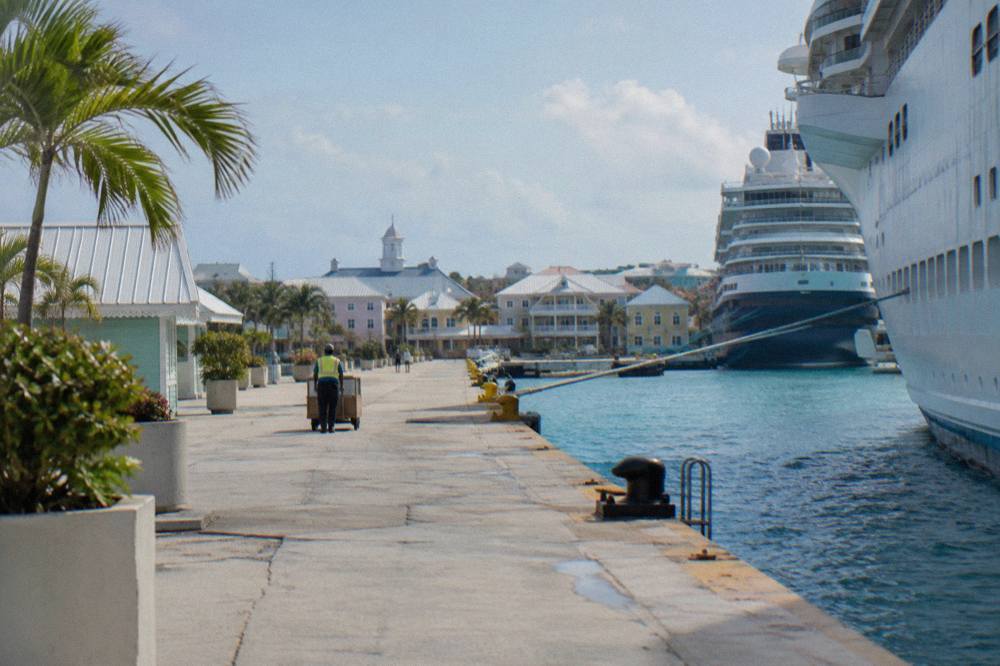 A walkway along the Nassau harbor with cruise ships and pastel buildings in the distance