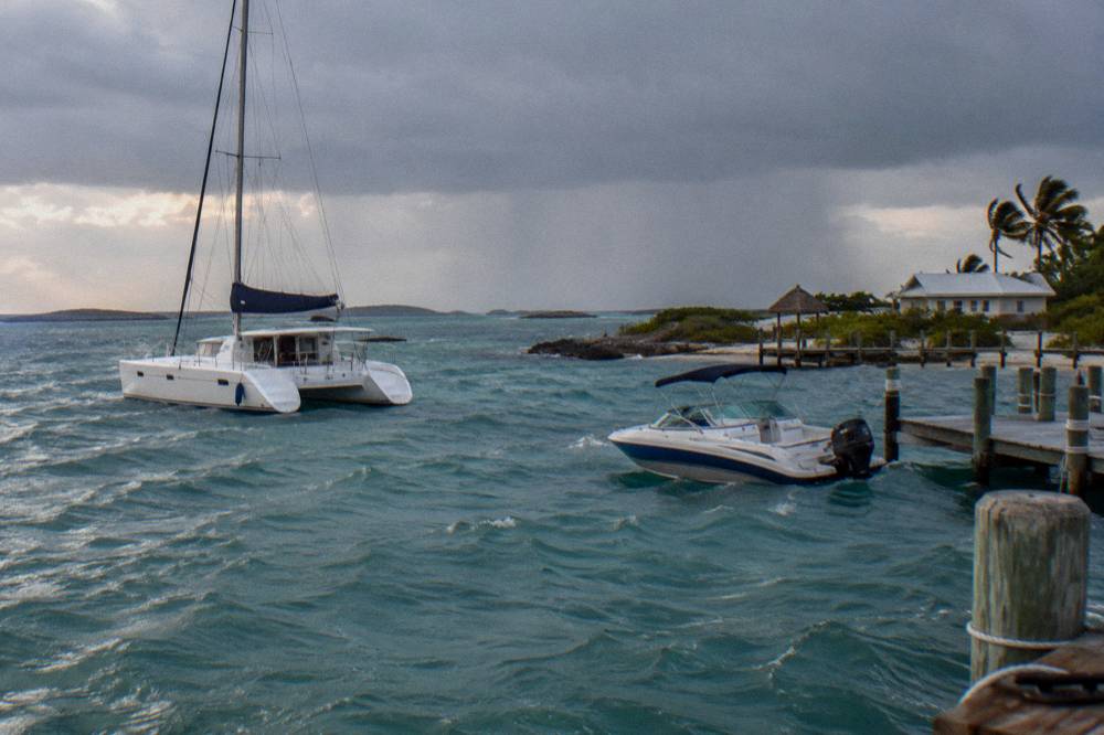 A catamaran and speedboat on open water under a partly cloudy tropical sky