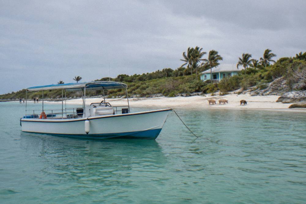 A tour boat anchored off a quiet beach with calm water and scattered clouds
