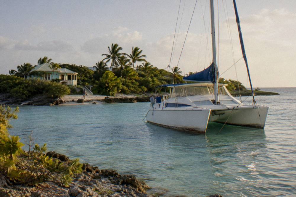 A catamaran moored in clear shallow water near a small green island
