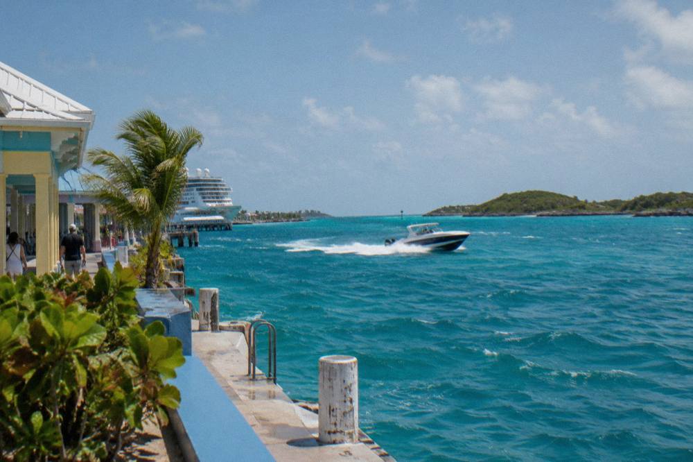 A twin-engine speedboat cutting across open turquoise water between low islands