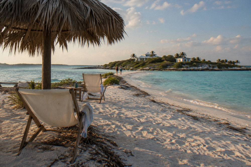 Shaded beach chairs and a thatched shade structure on a narrow sand spit