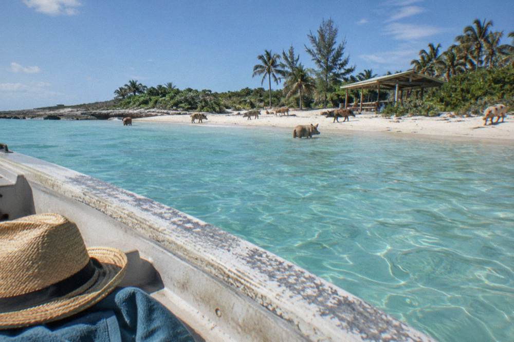 A straw hat, towel and sunscreen bottle arranged on the gunwale of a boat