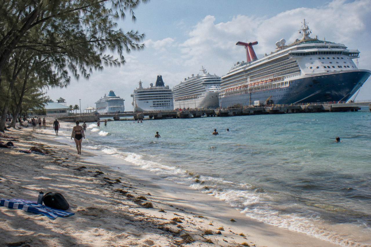 Wide view of a calm Nassau beach with pale sand and clear shallow water along the shoreline