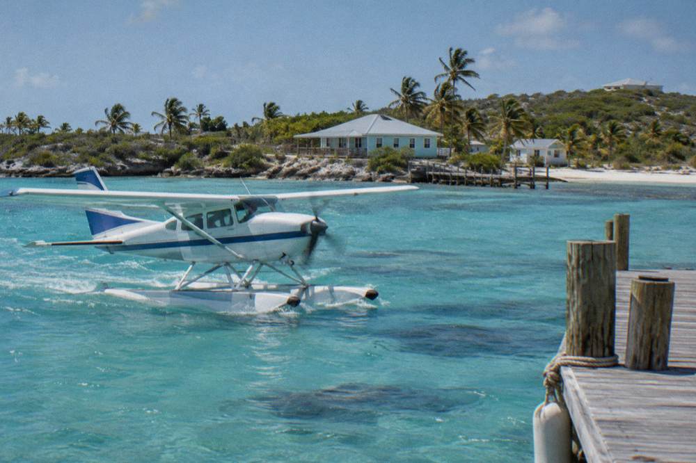 A small charter floatplane over bright blue Exuma shallows