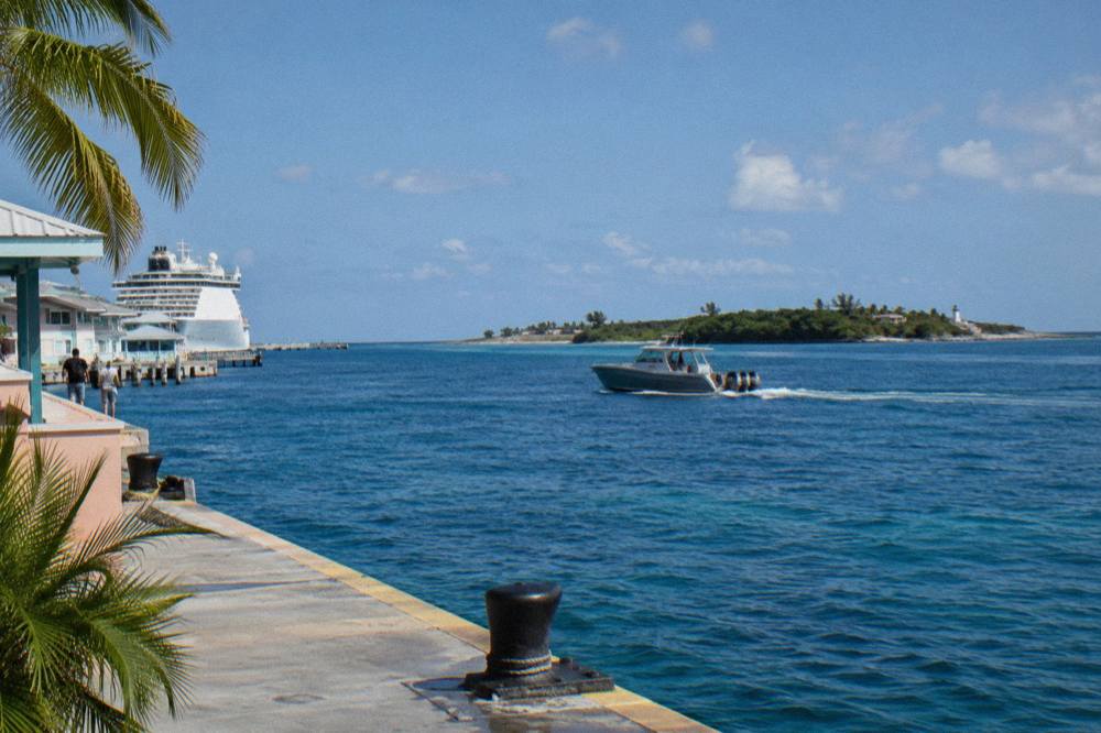 A powerboat crossing calm blue water toward a green island on the horizon