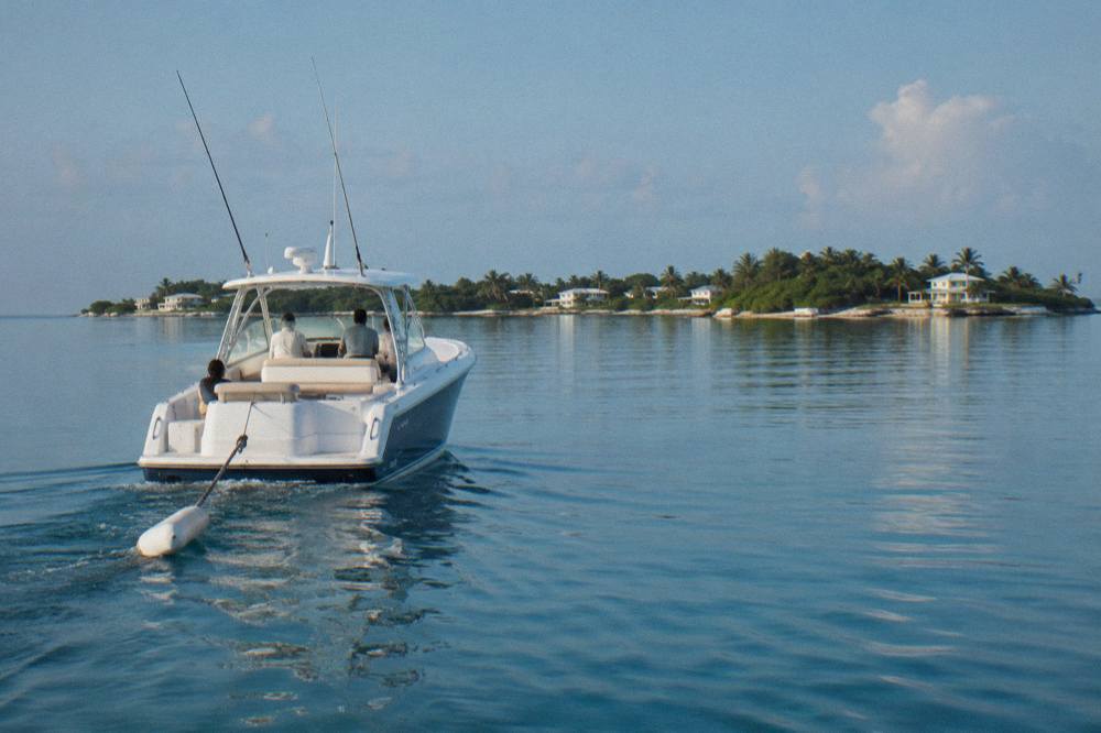 A private charter boat cruising across calm turquoise water toward a small island