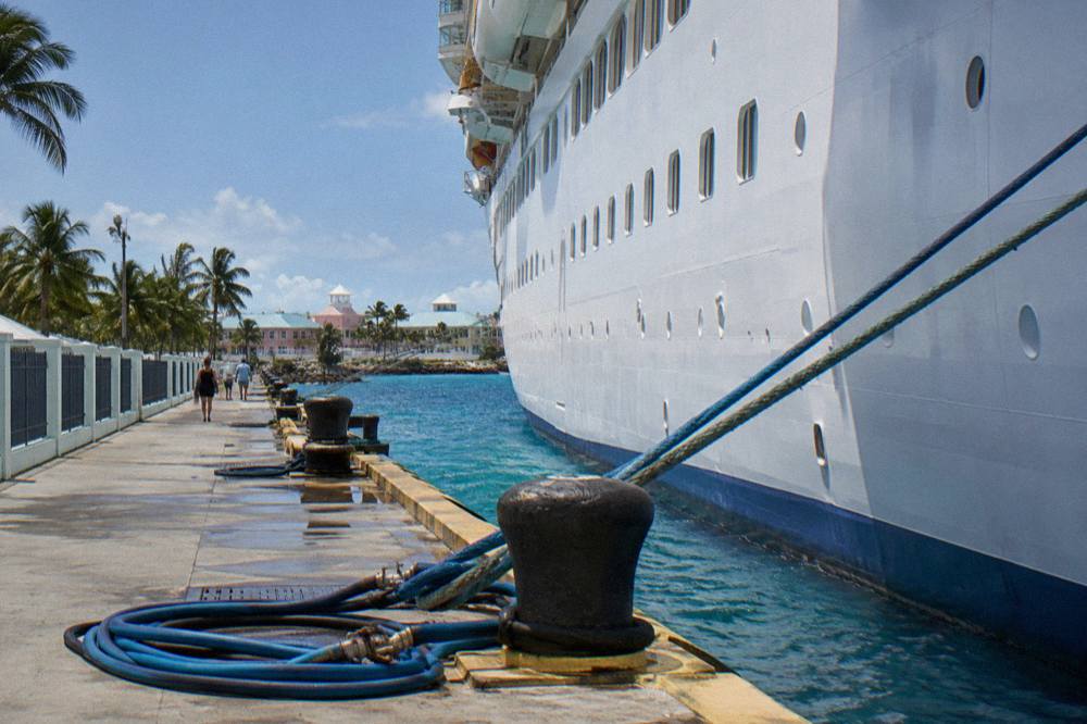 A cruise ship docked at a waterfront port terminal in Nassau with tour boats nearby