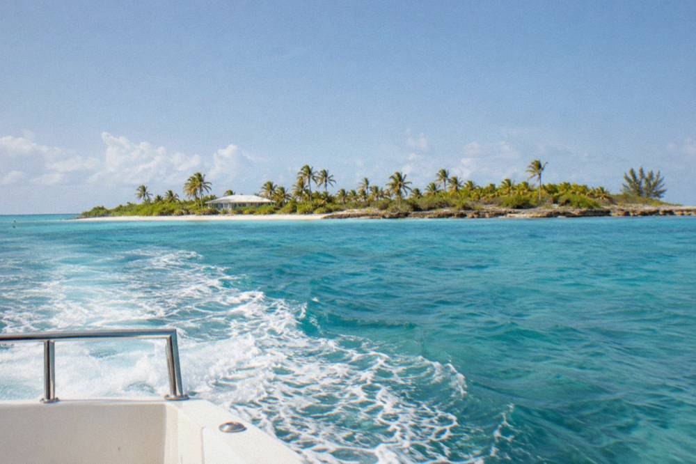 A speedboat crossing open turquoise water toward small Bahamian cays