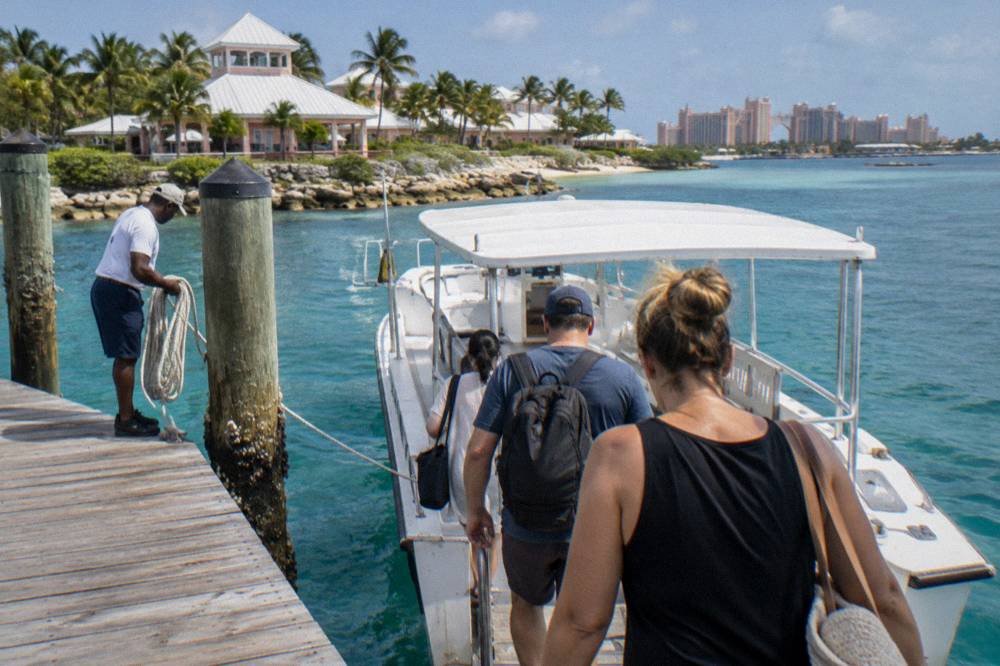 Passengers boarding a small tour boat at a wooden dock in a harbor