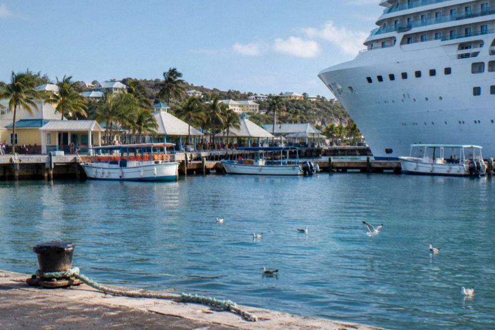A cruise ship docked at a waterfront terminal with small boats moored in the foreground