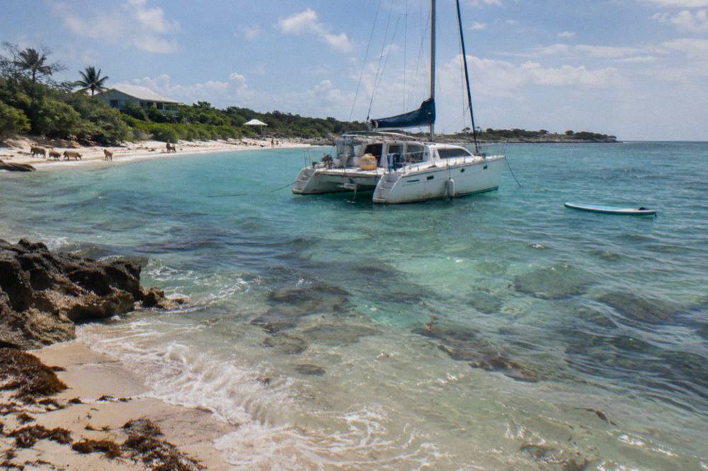A small catamaran anchored near a coral reef in turquoise water