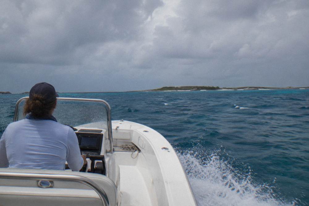 Open speedboat crossing blue open water toward low islands on the horizon