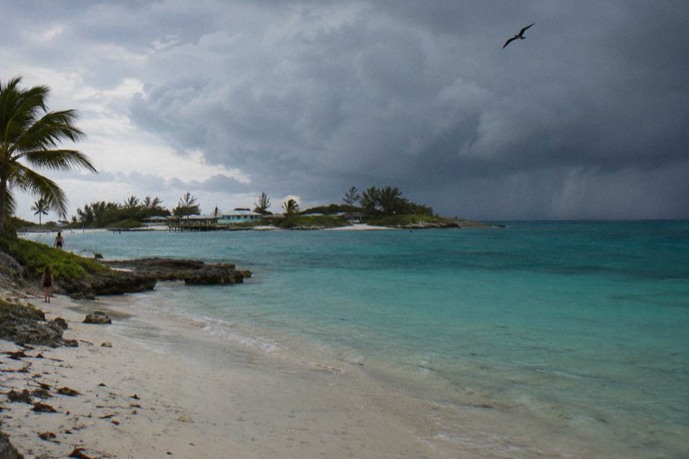 Turquoise water off a small island with clouds building on the horizon