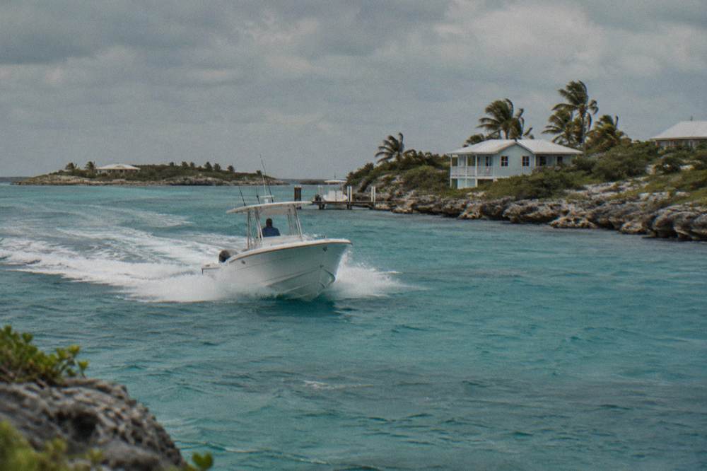 A powerboat cutting across open turquoise water toward small cays on the horizon