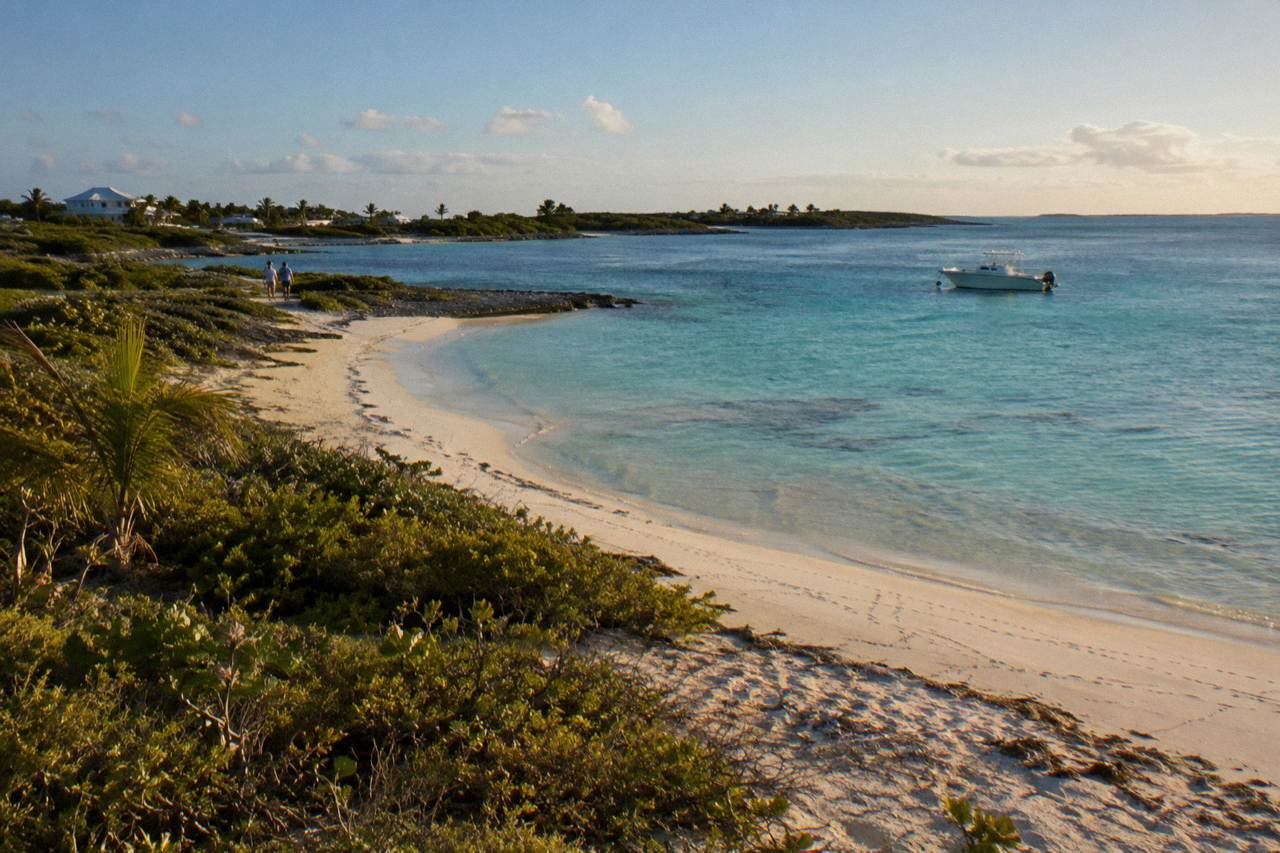Turquoise shallows around a small Bahamian island with a boat anchored offshore