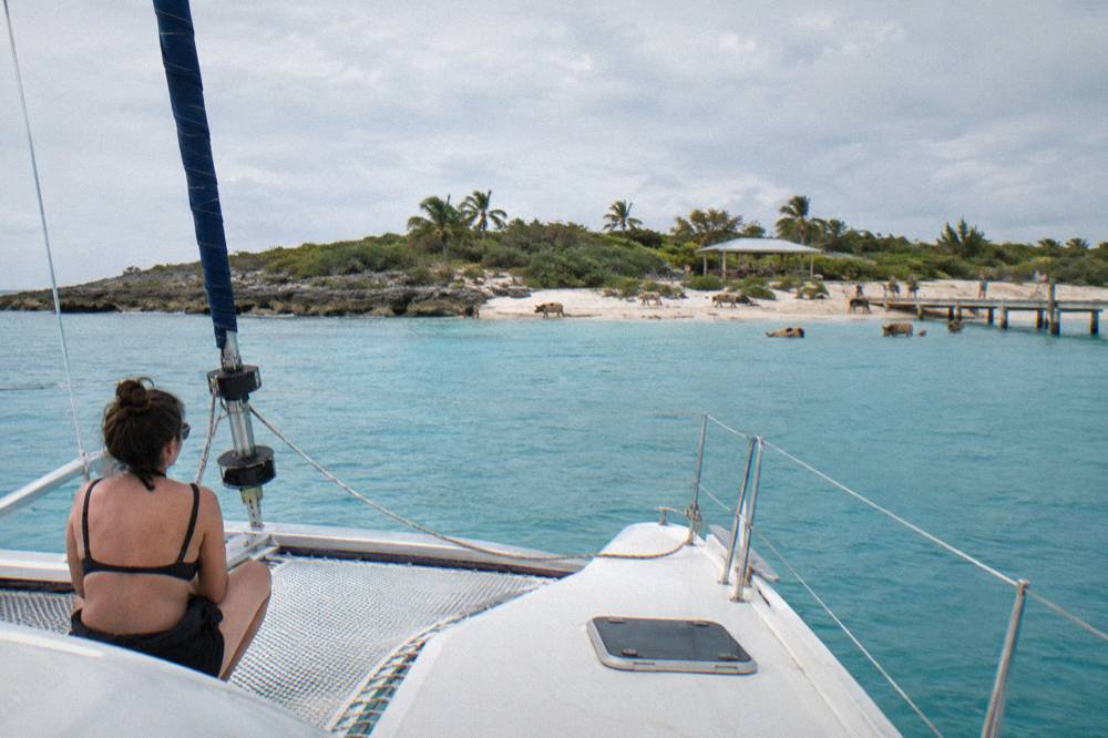 A wide catamaran deck on calm water with an island in the distance