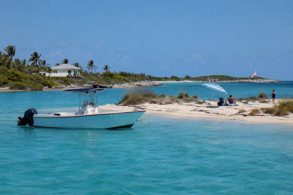 A family-sized boat moored beside a small beach island in bright light