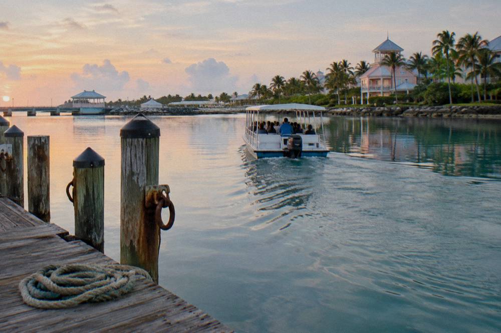 A small boat pulling away from a wooden dock in the early morning calm