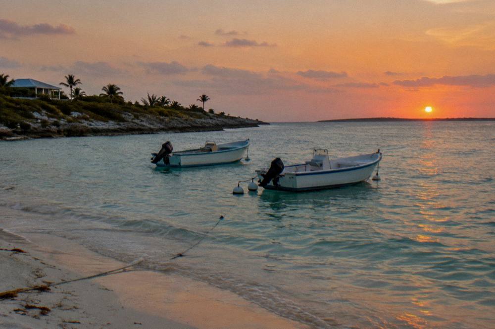 Sunset over a calm anchorage with boats moored near an island beach
