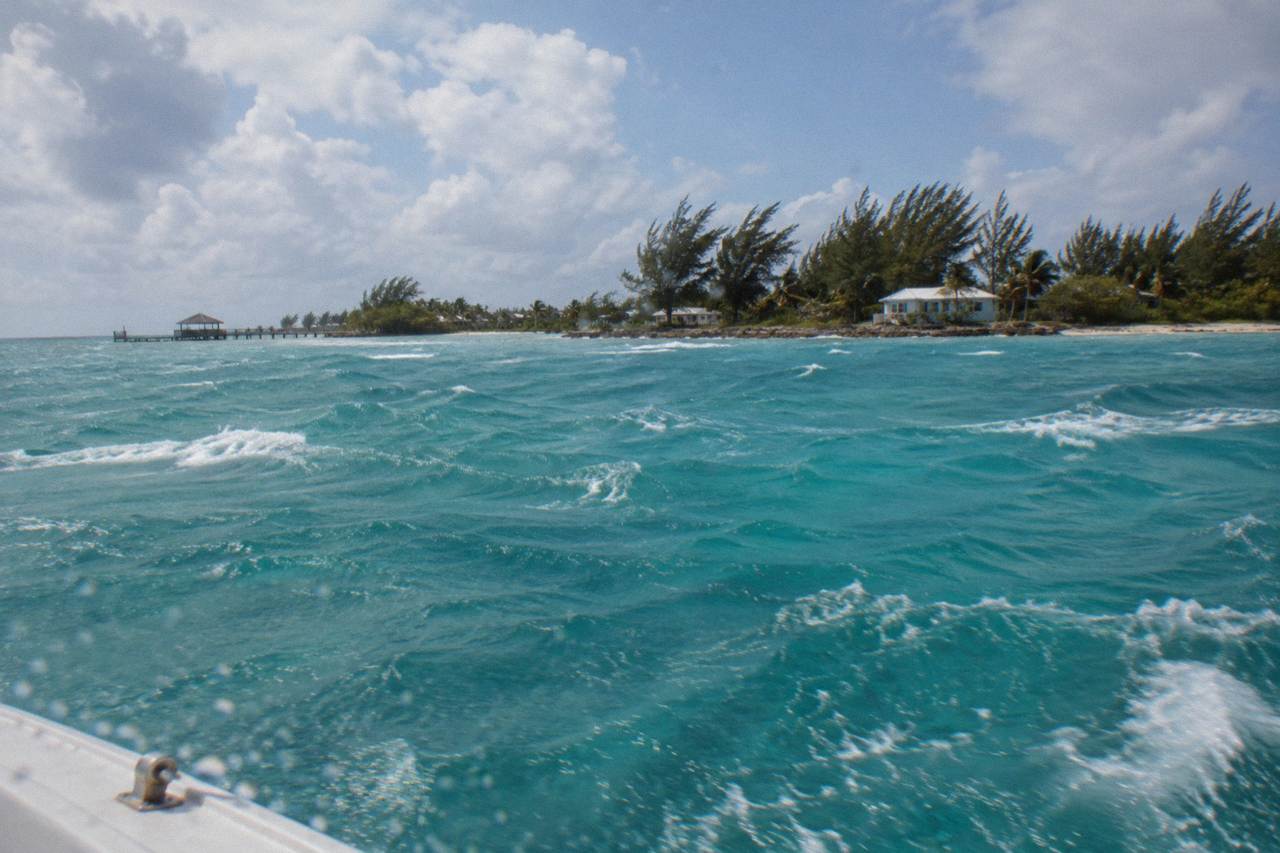 Open turquoise water between Nassau and a small offshore island under a partly cloudy sky