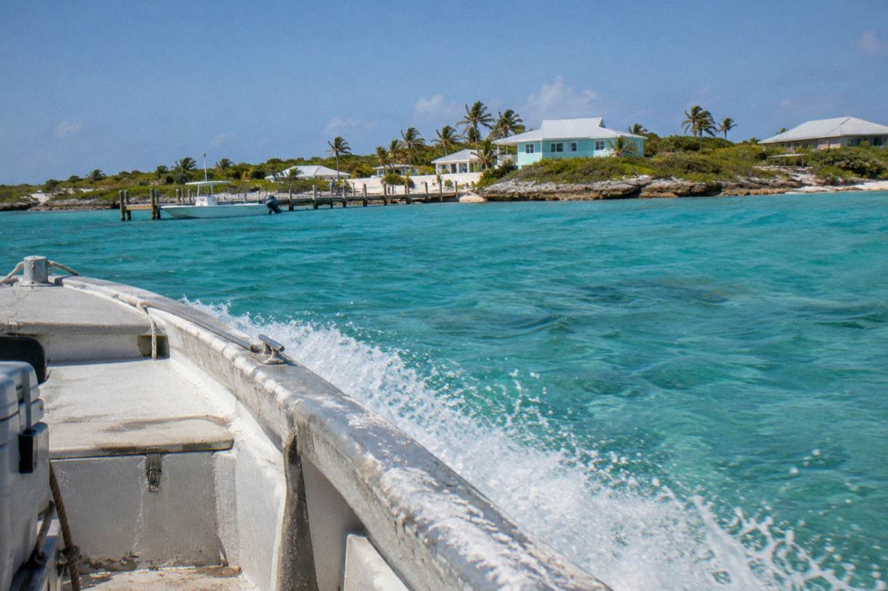 Open powerboat cutting across clear turquoise water toward small cays