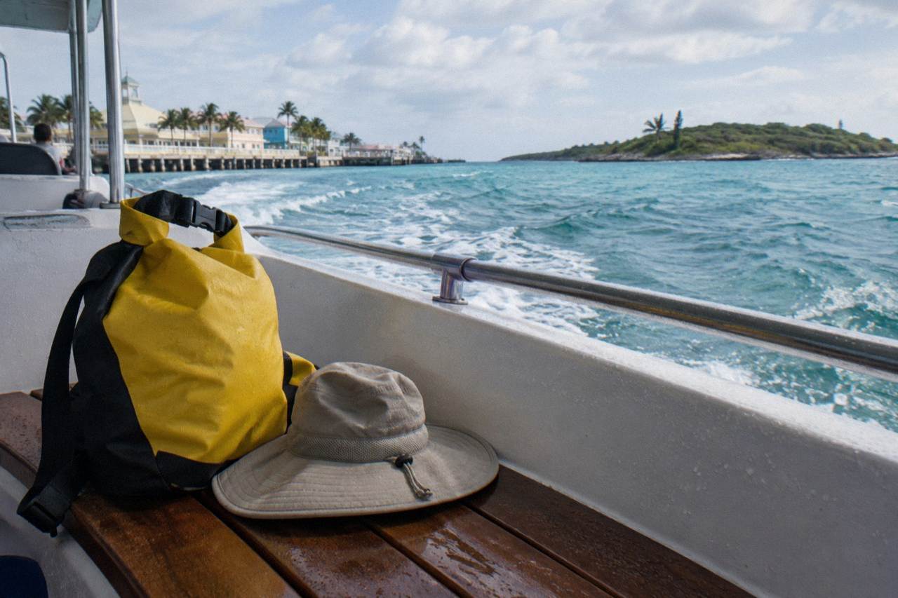 A beach bag, sun hat and towels on the deck of a boat headed toward a small Bahamian island