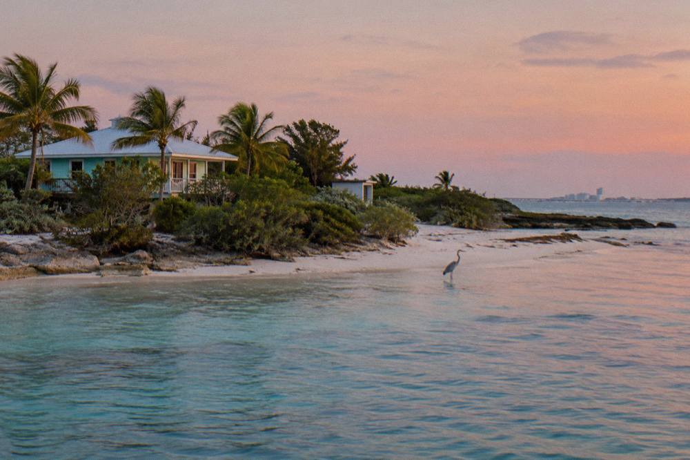 A small uninhabited Bahamian cay with pale sand and clear shallow water on a calm morning