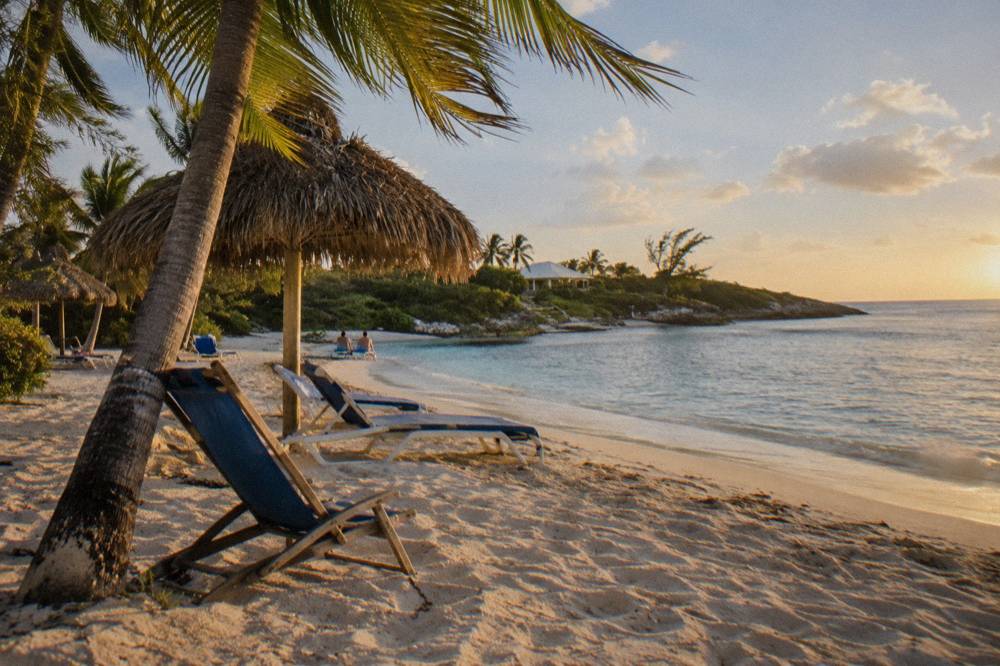 Beach chairs and shaded seating on a small private Bahamian island beach