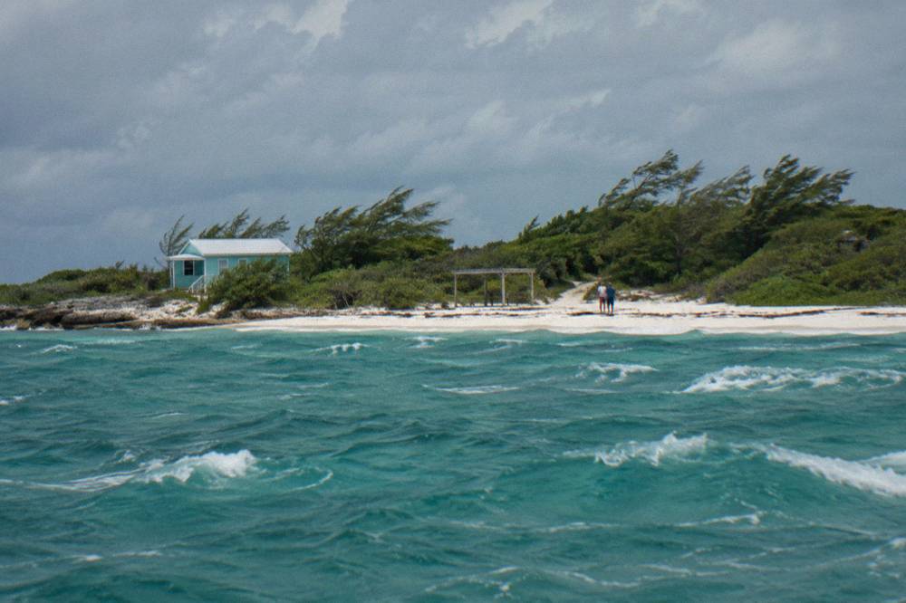 An uninhabited tropical cay with white sand and turquoise shallows seen from open water